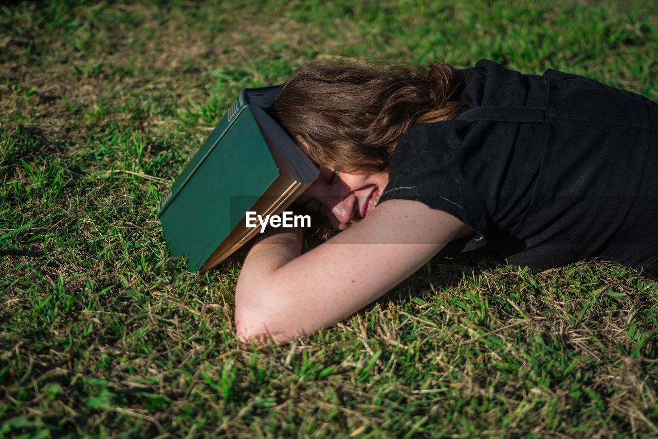 High angle view of woman with book lying on field