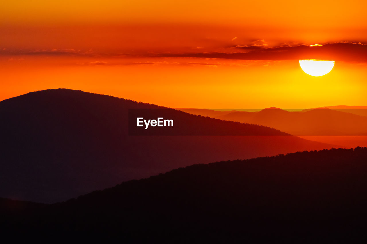 Scenic view of silhouette mountains against romantic sky at sunset