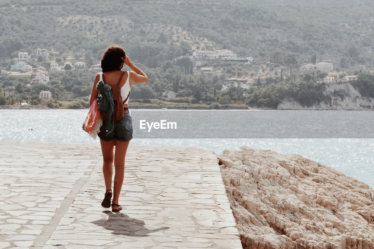 Rear view of woman walking on footpath by sea