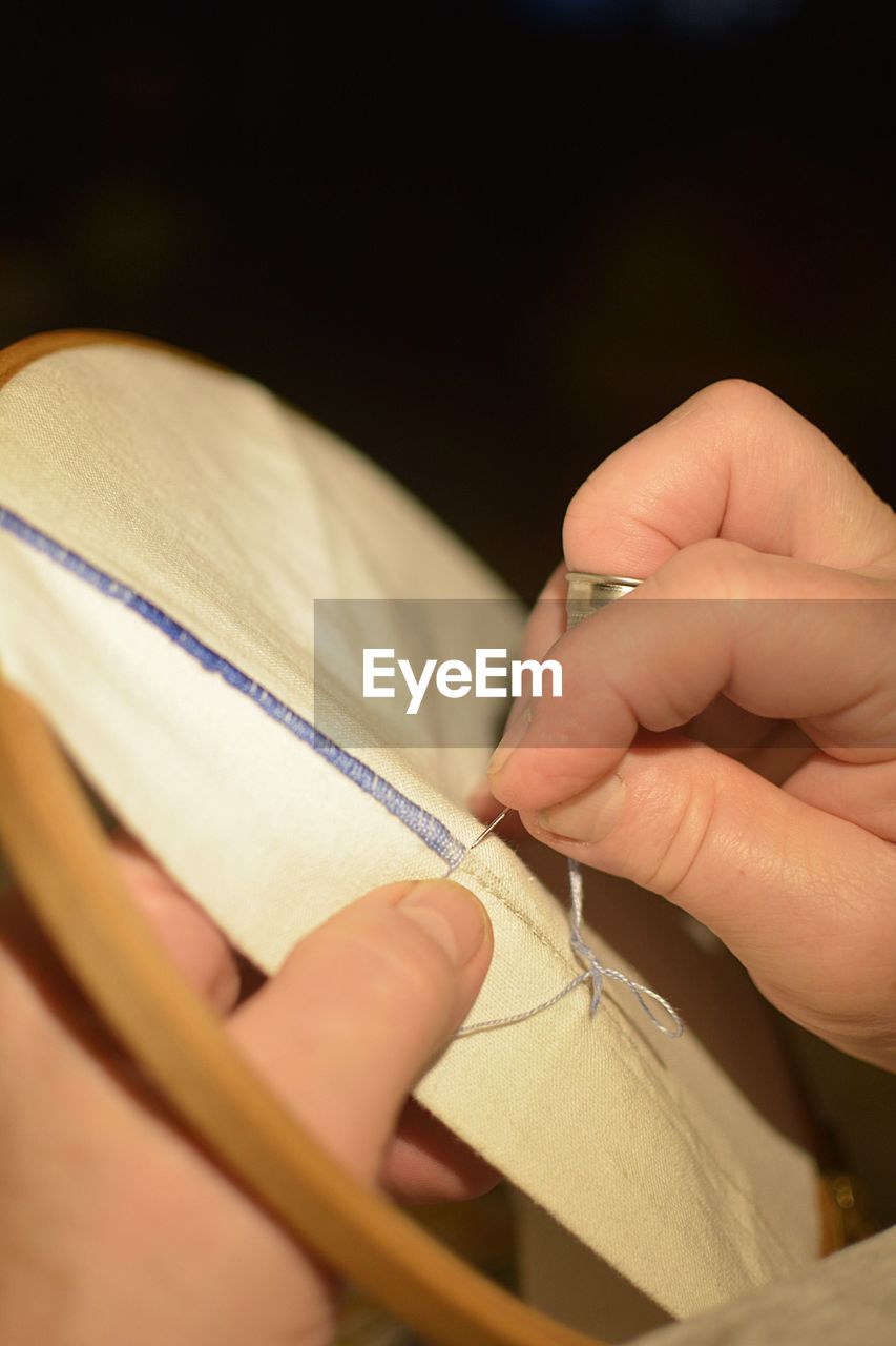 Cropped hands of woman doing embroidery on textile