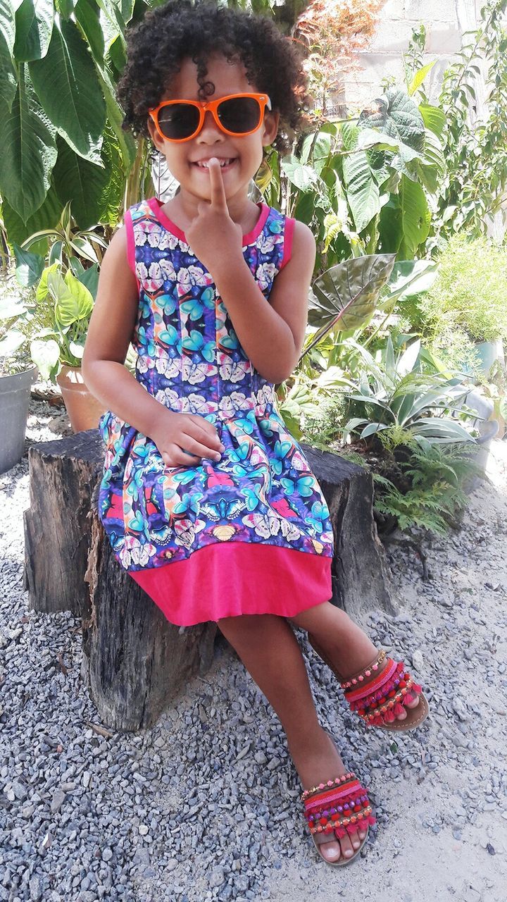 PORTRAIT OF YOUNG WOMAN WEARING SUNGLASSES STANDING AGAINST TREES