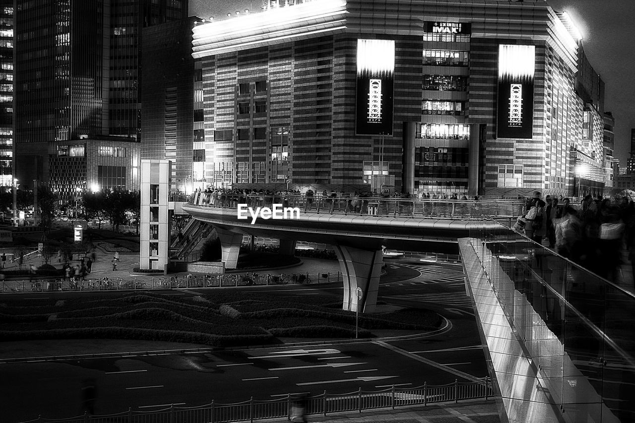 People on bridge by building at night