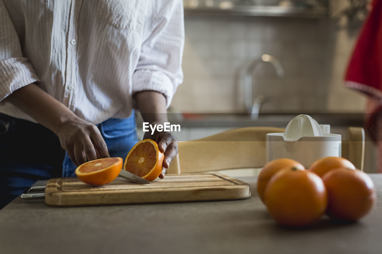 Young woman cutting oranges, partial view