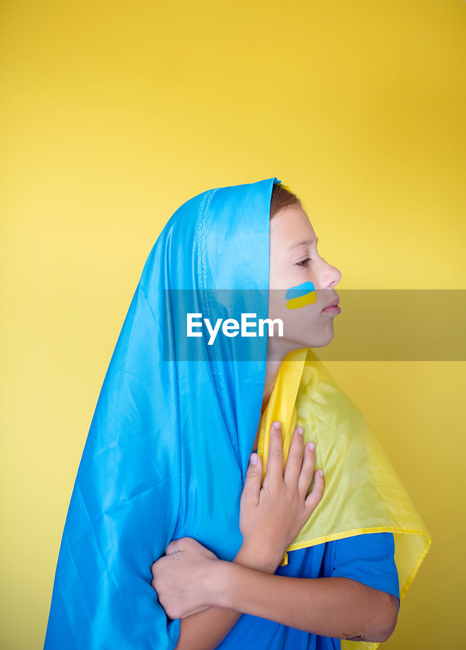 Close-up of woman with face against yellow background