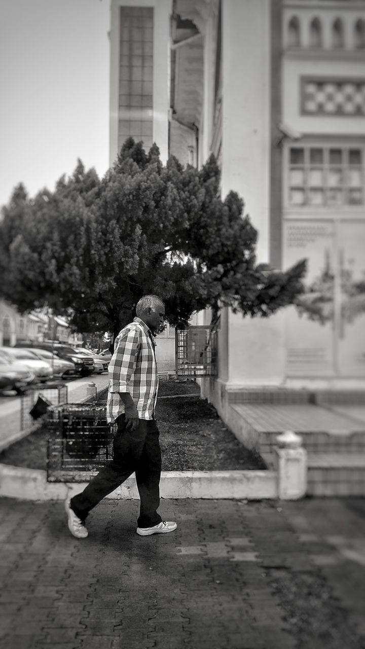 FULL LENGTH REAR VIEW OF MAN WALKING ON CITY STREET