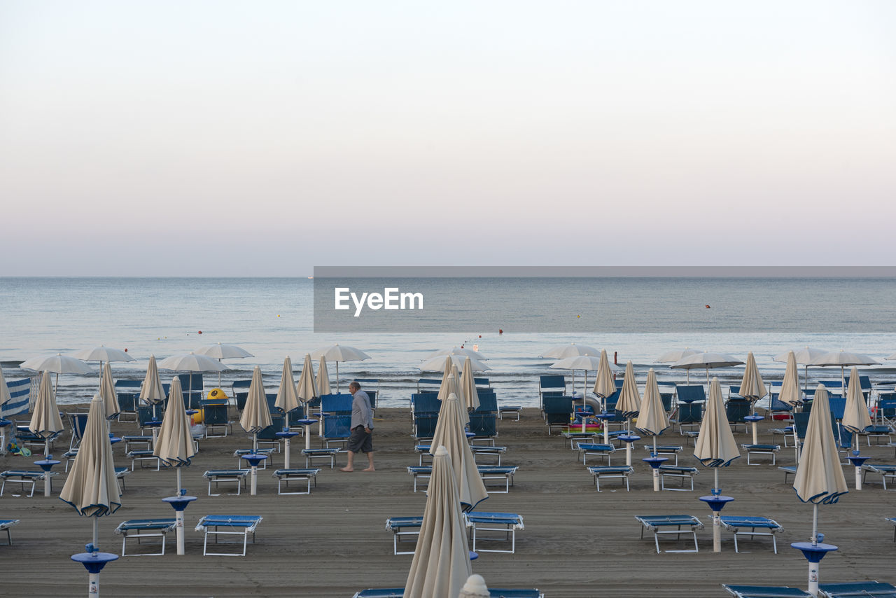 CHAIRS ON BEACH AGAINST SKY DURING SUNSET