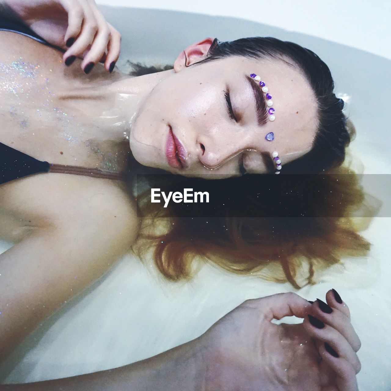 Woman with decorated face lying down in bathtub