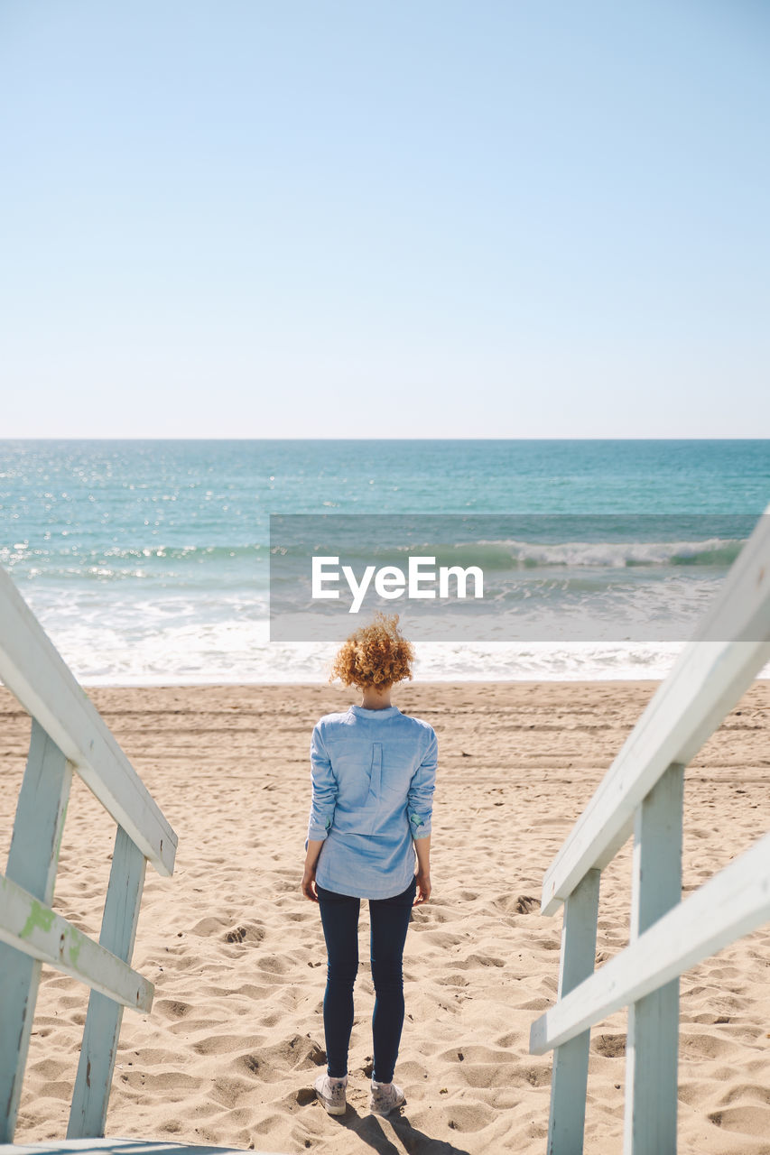 High angle view of mid adult woman standing by footpath at beach