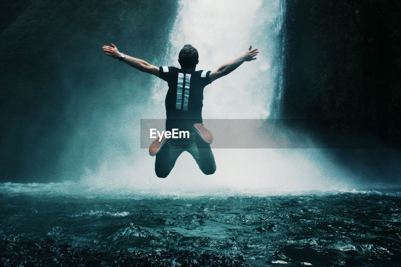 Man jumping in waterfall