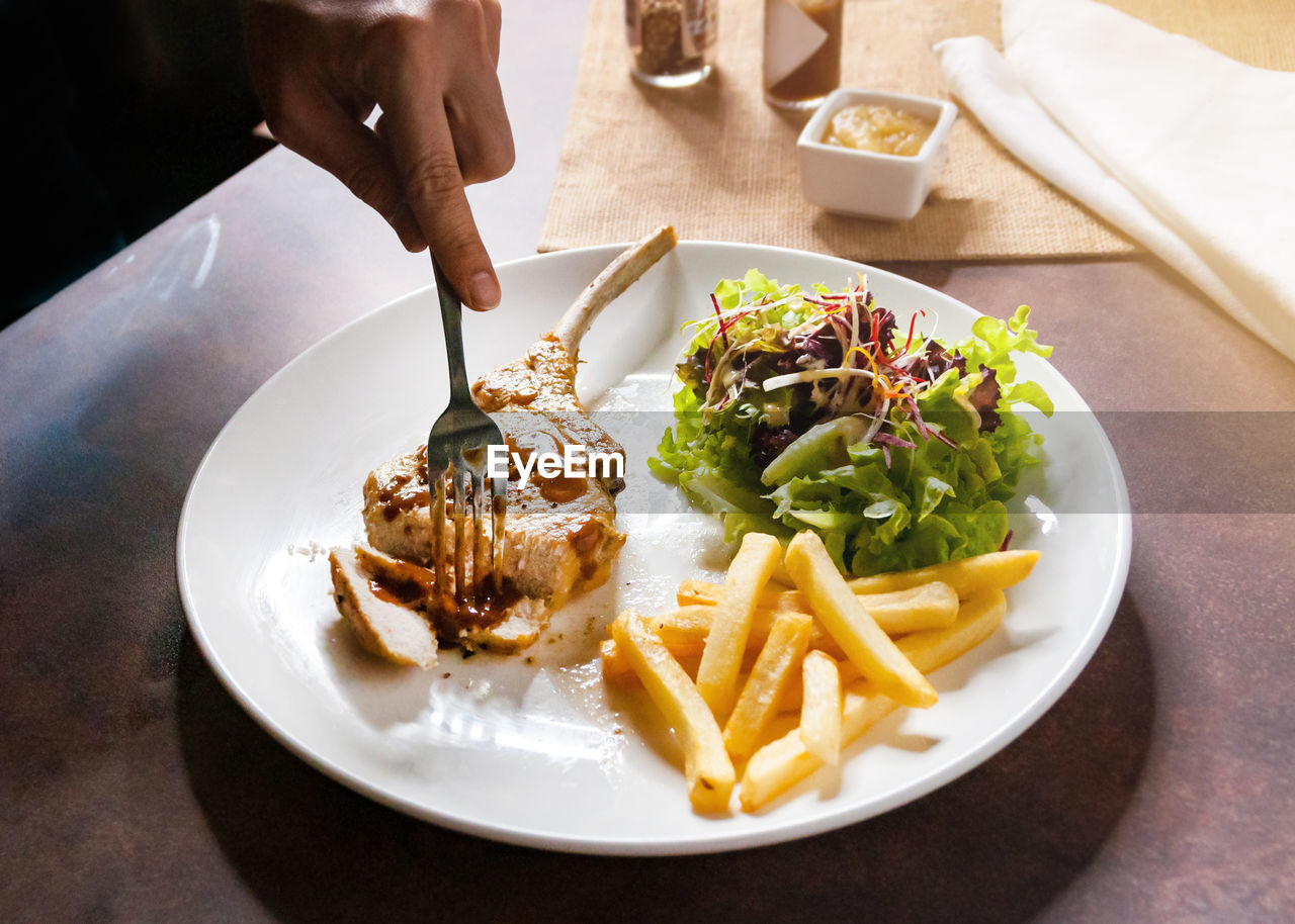 cropped hand of person having food on table