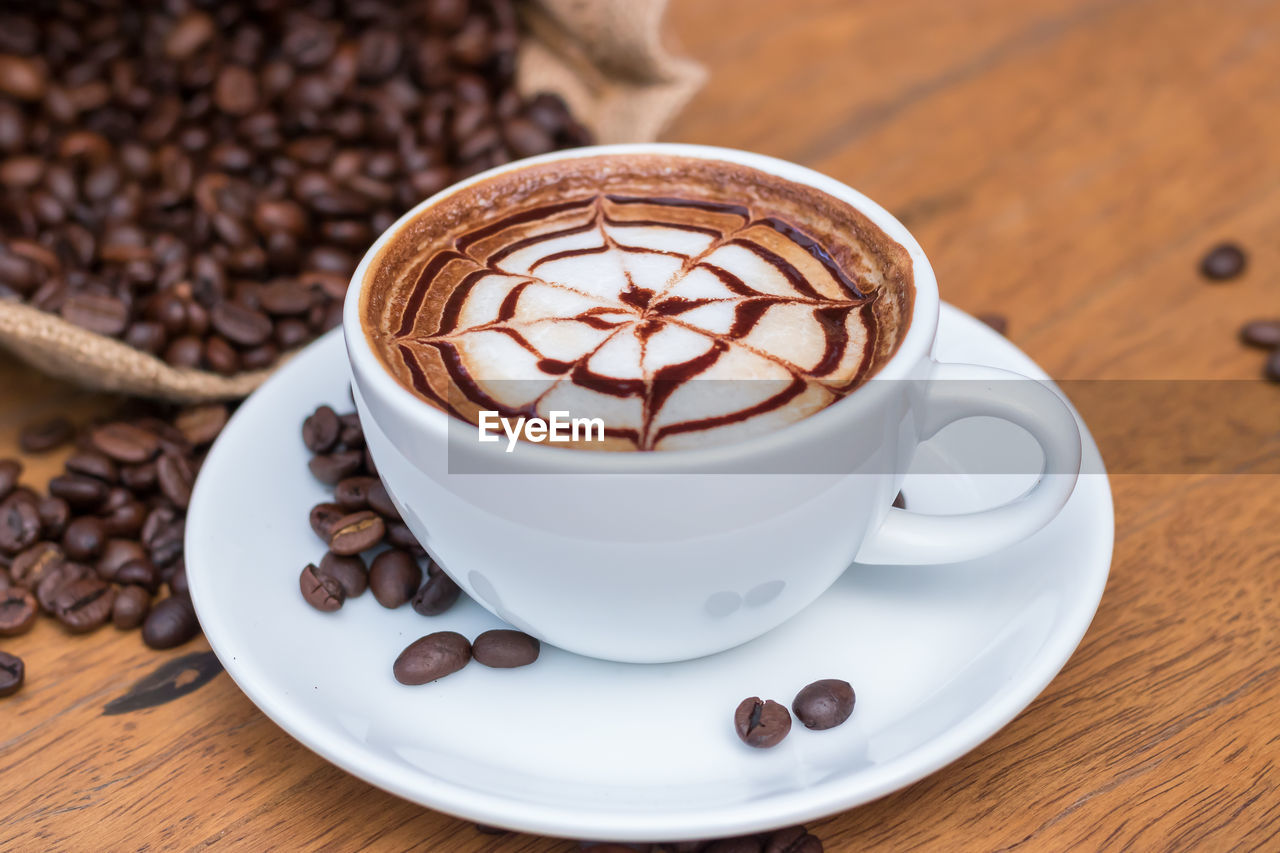 Close-up of coffee cup and beans on table