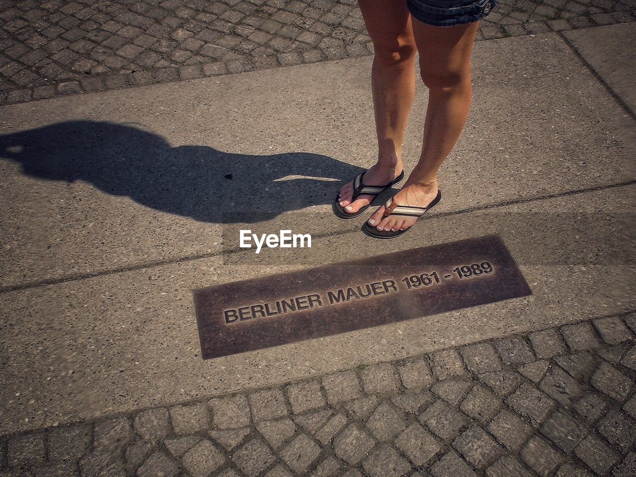 Low section of woman standing on cobblestone