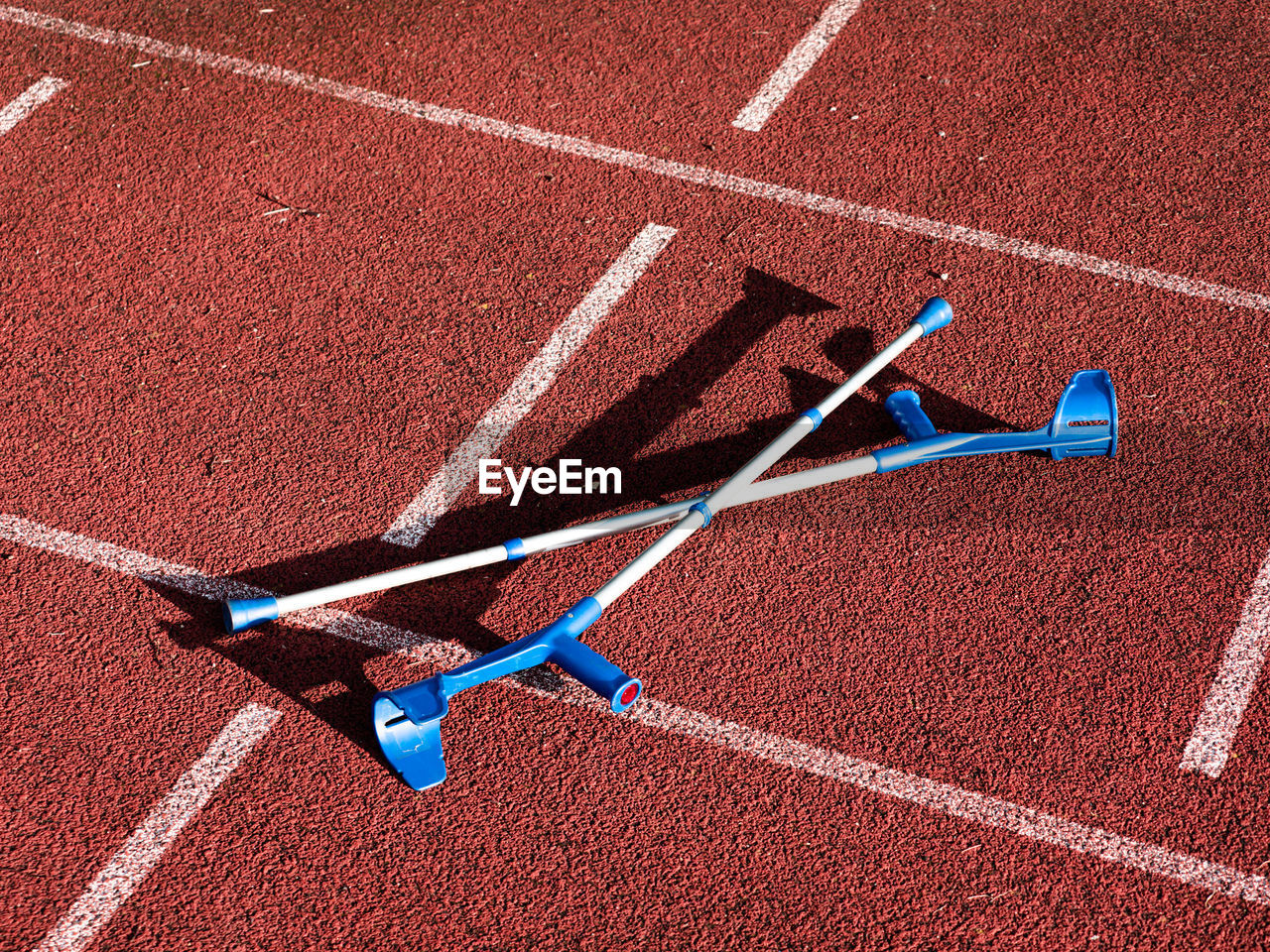 Forearm crutches on red running track on stadium. run lines on front tracks