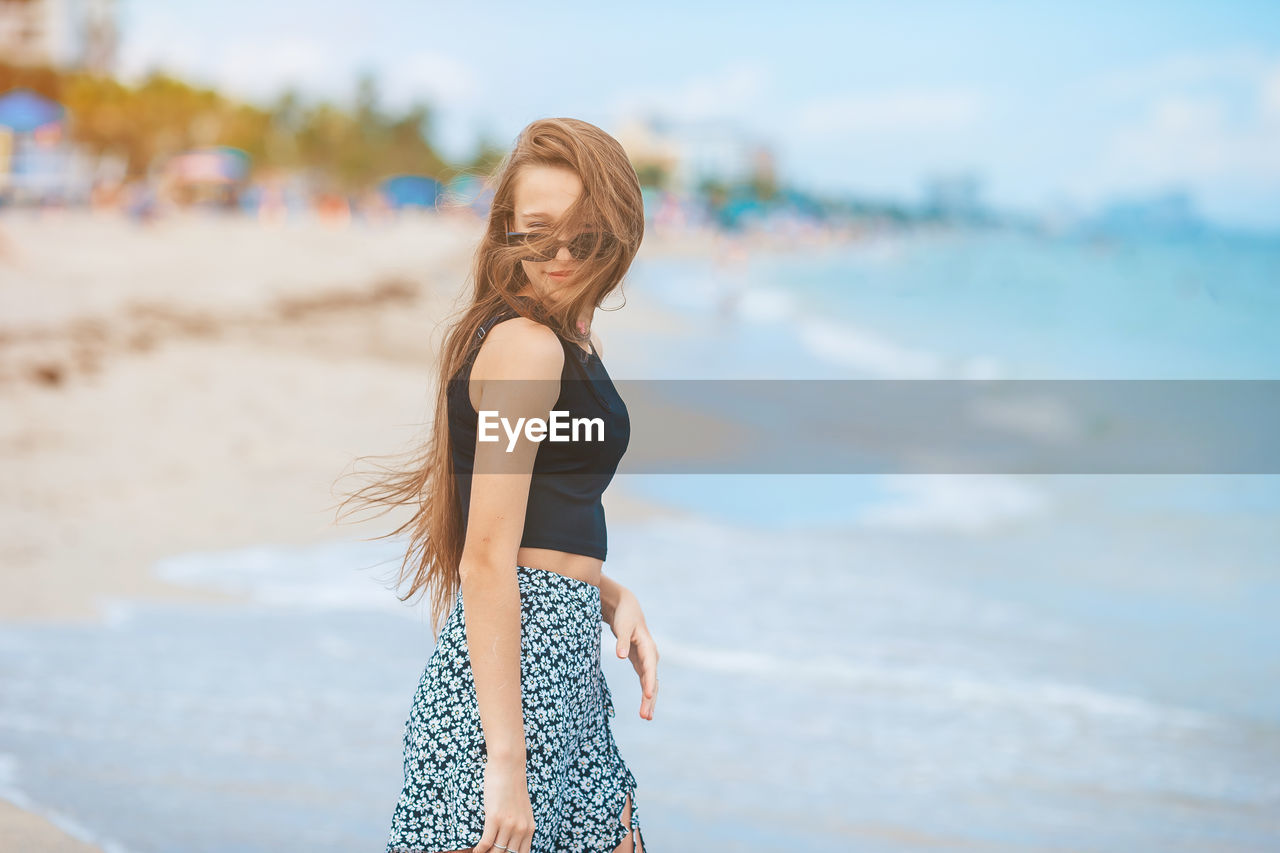 side view of young woman standing at beach