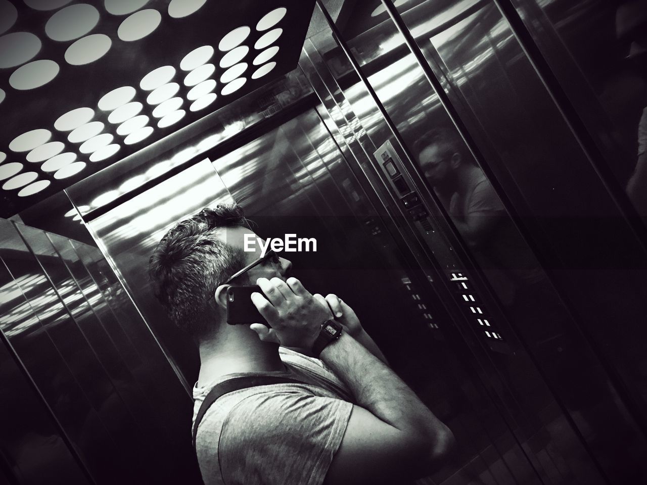 Tilt image of man using smart phone in elevator