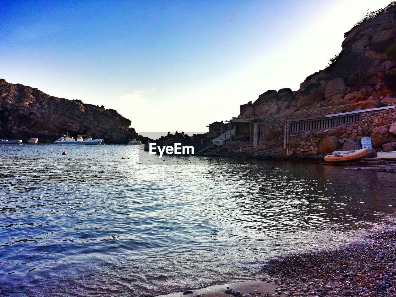 Boats moored on sea by mountain against sky