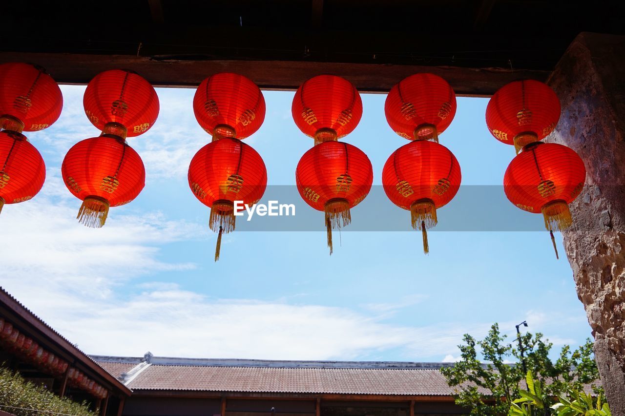 Low angle view of lanterns hanging ceiling against sky