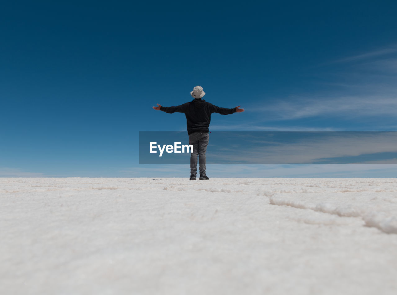 Rear view of man standing on landscape against sky