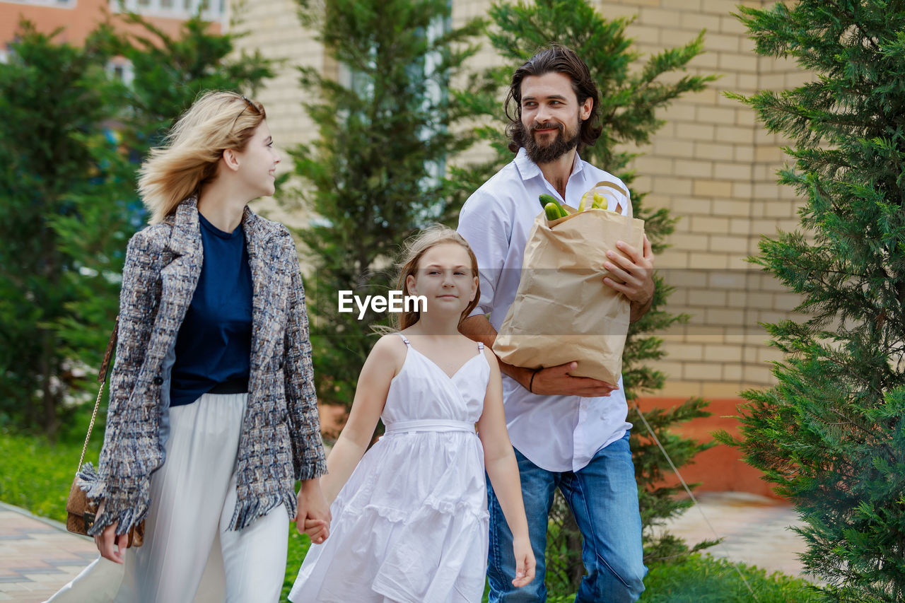 Parents with daughter walking against trees