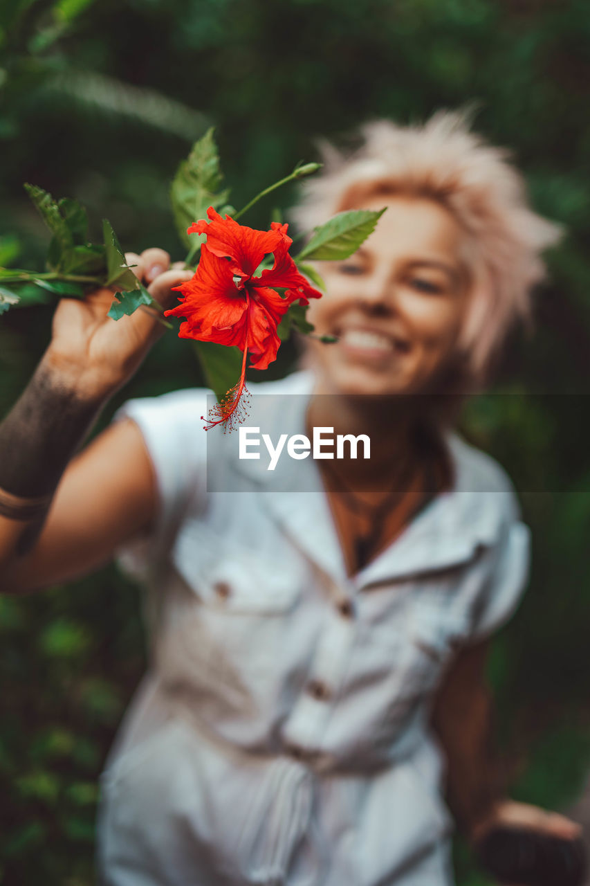 Smiling woman holding red flower