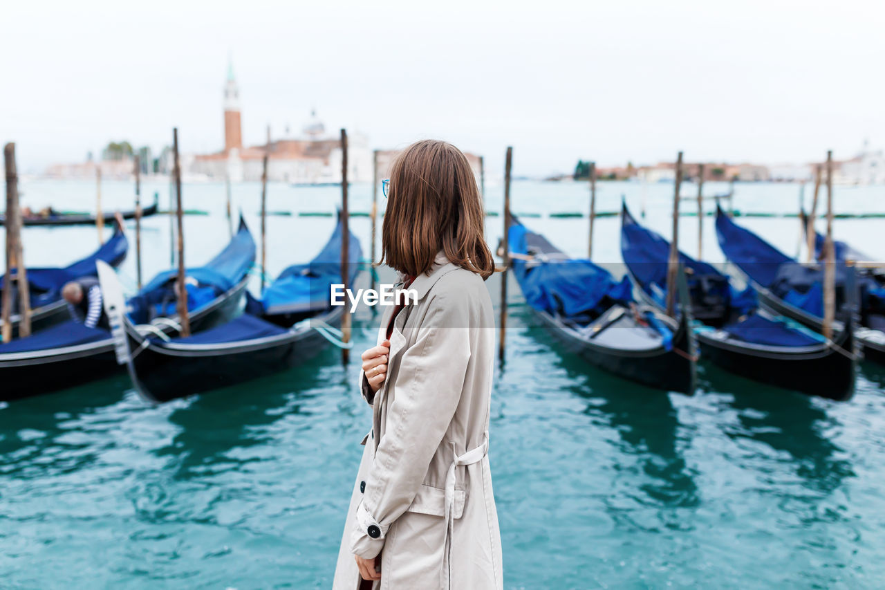 Girl in a dress and coat on the background of the canal and gondola