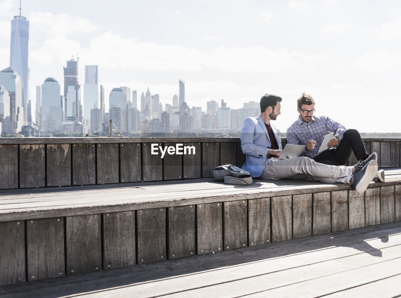 Usa, two businessmen working at new jersey waterfront with view to manhattan