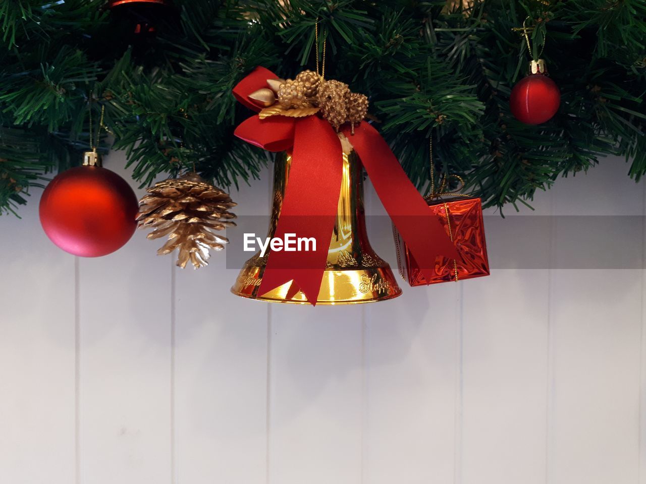 Close-up of christmas decorations hanging against white wooden wall