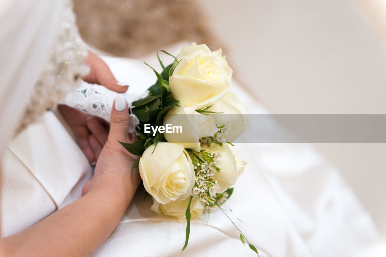 Midsection of bride holding flower bouquet