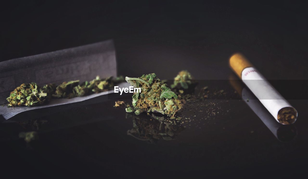 Close-up of cigarette on table against black background