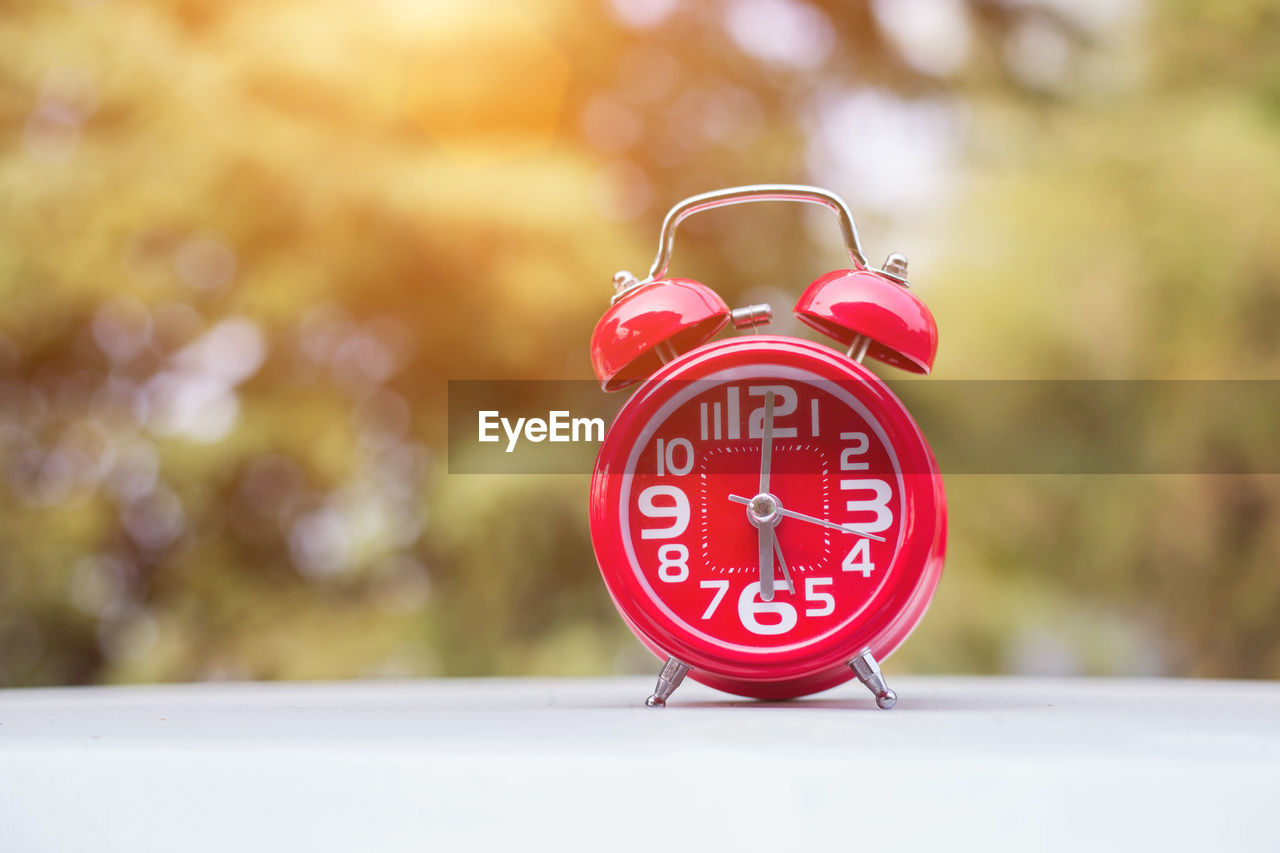 Close-up of red alarm clock on table at yard