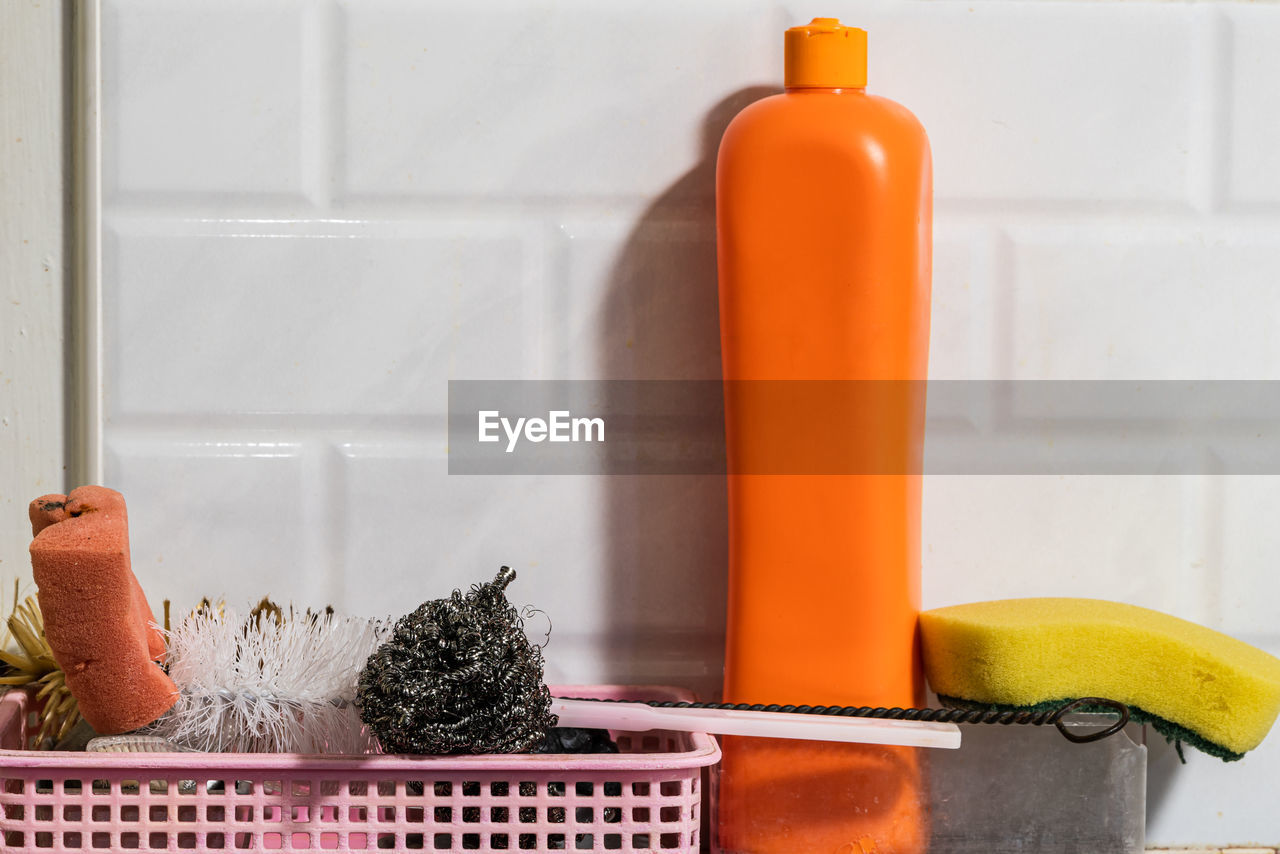 CLOSE-UP OF ORANGE BOTTLE ON TABLE