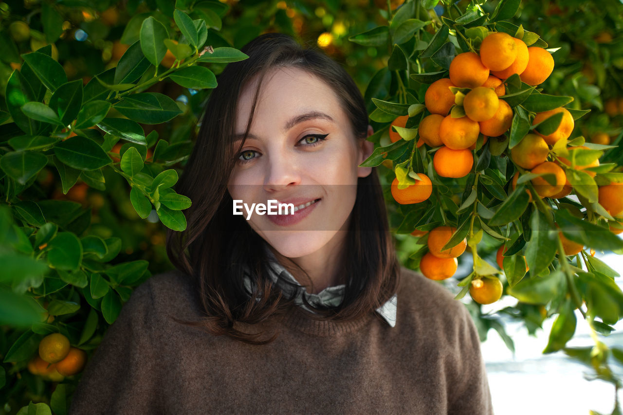 portrait of smiling young woman standing amidst plants