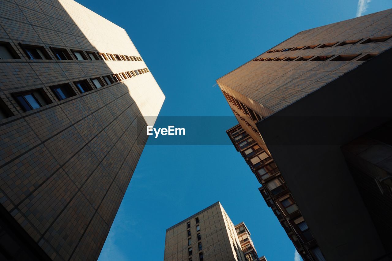 Low angle view of modern buildings against clear blue sky