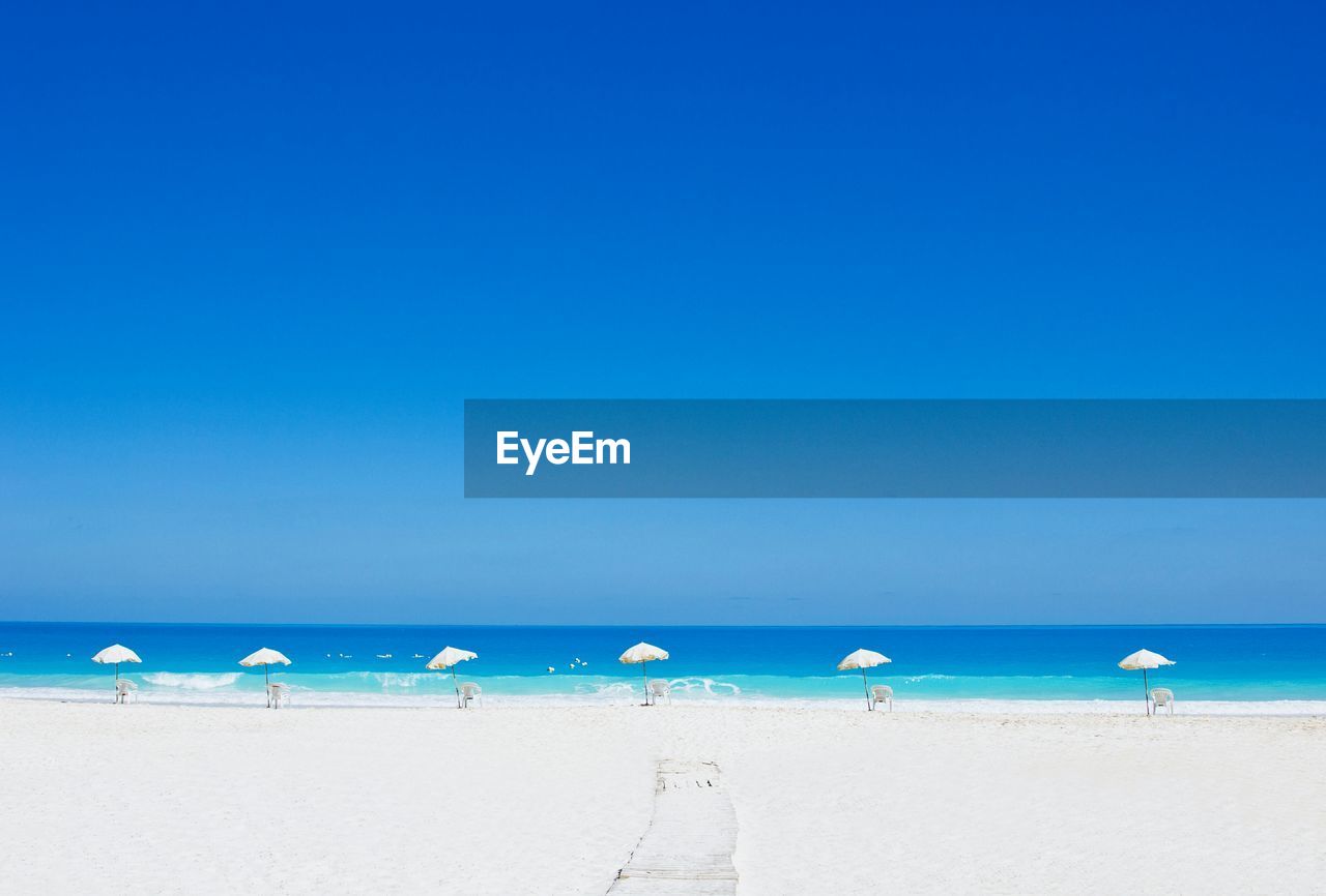 Parasols on beach against clear blue sky