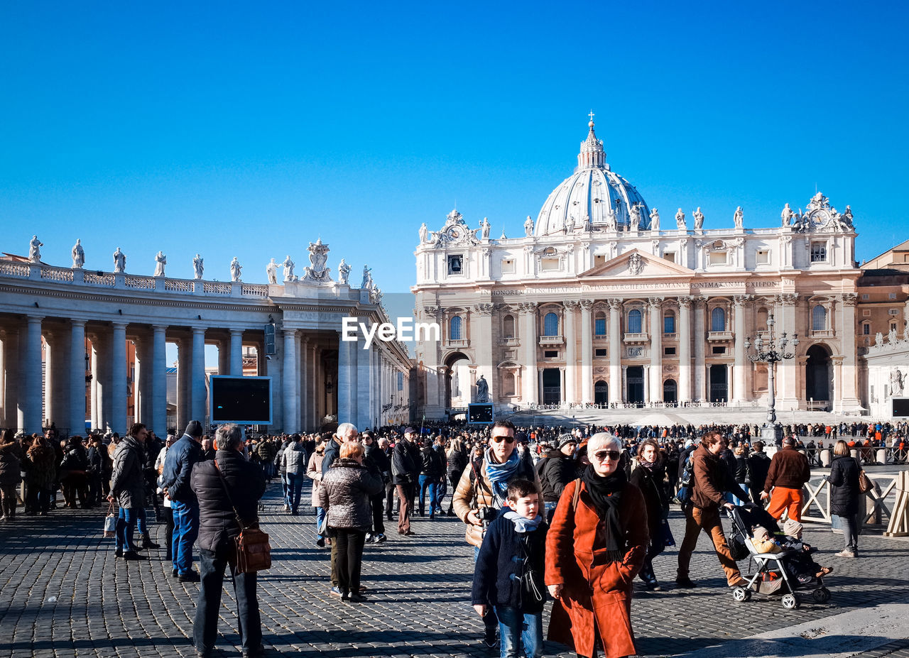 People at st peters square in city against clear blue sky