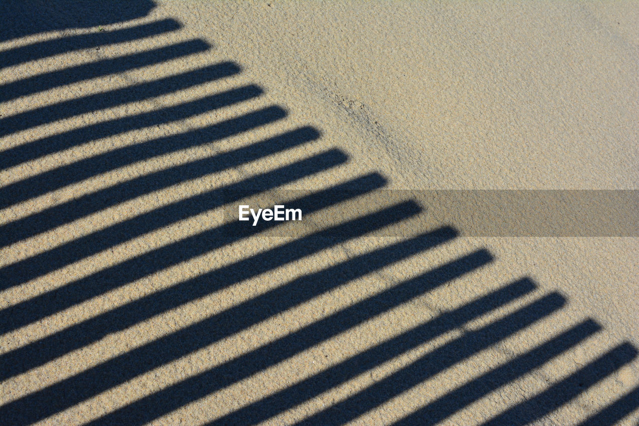 HIGH ANGLE VIEW OF SHADOW ON SAND AT PARK