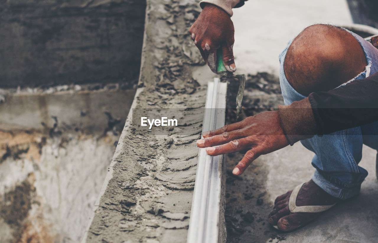 LOW SECTION OF MAN WORKING BY STONE