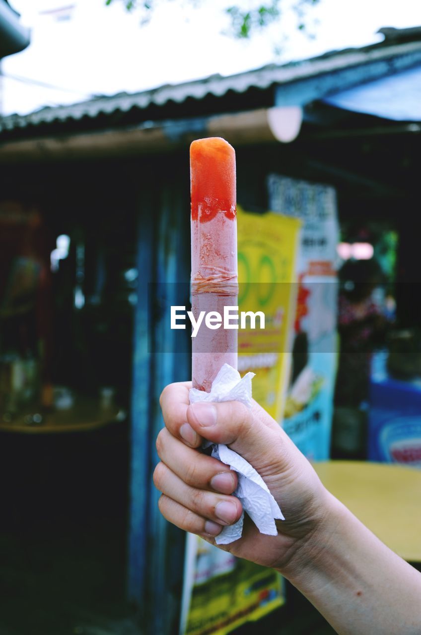 CLOSE-UP OF HUMAN HAND HOLDING ICE CREAM