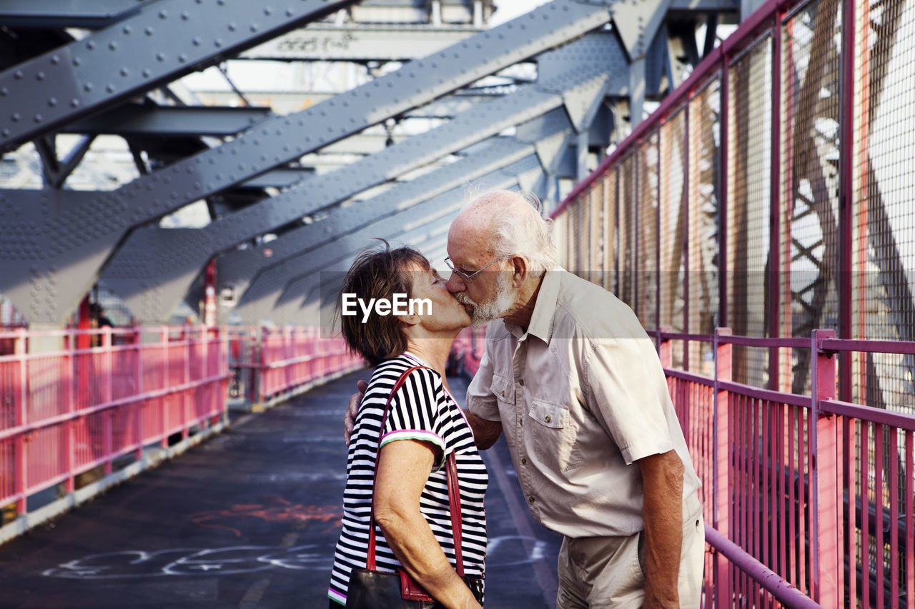 Senior couple kissing on bridge