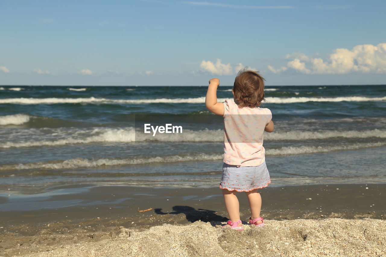 REAR VIEW OF CHILD STANDING ON BEACH