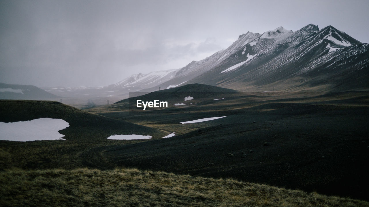 Scenic view of snowcapped mountains against cloudy sky