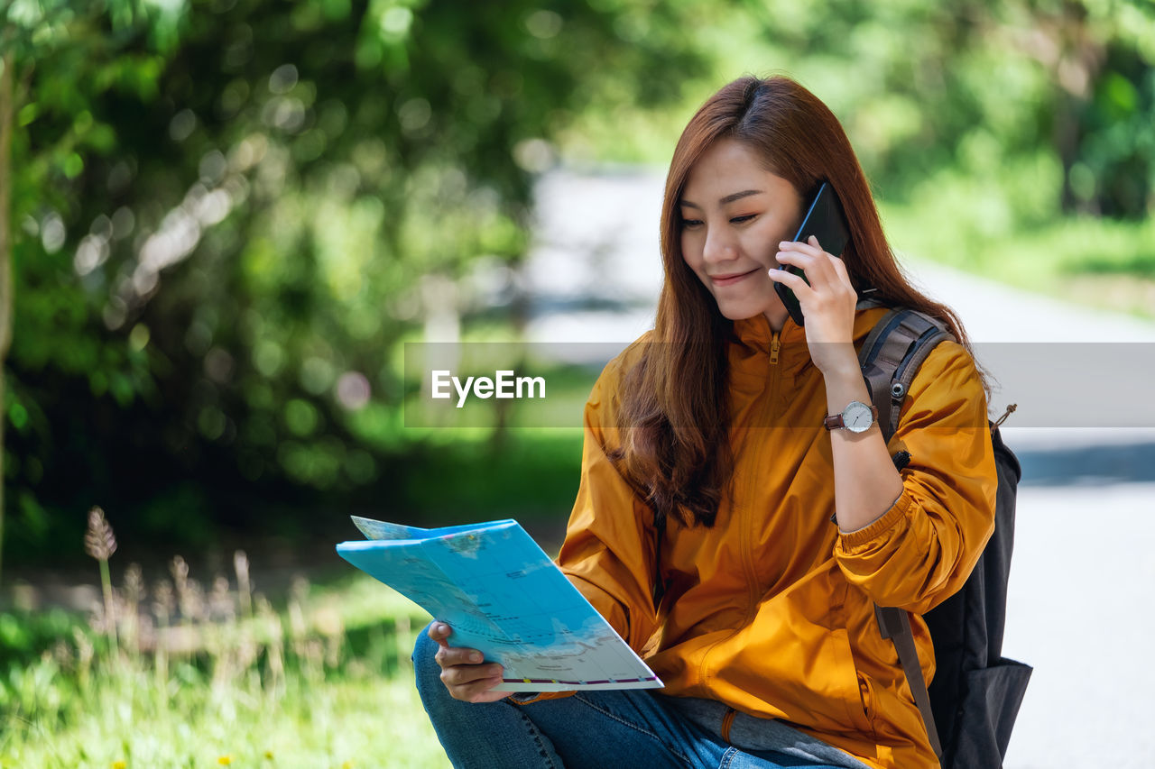 Young woman using laptop while sitting on field