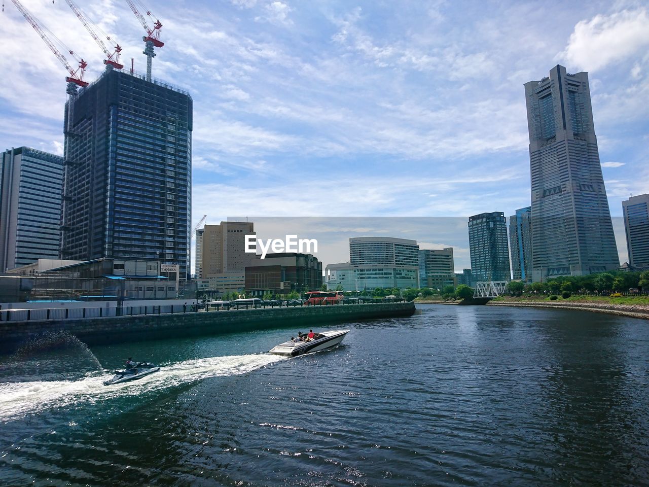 MODERN BUILDINGS BY RIVER AGAINST SKY