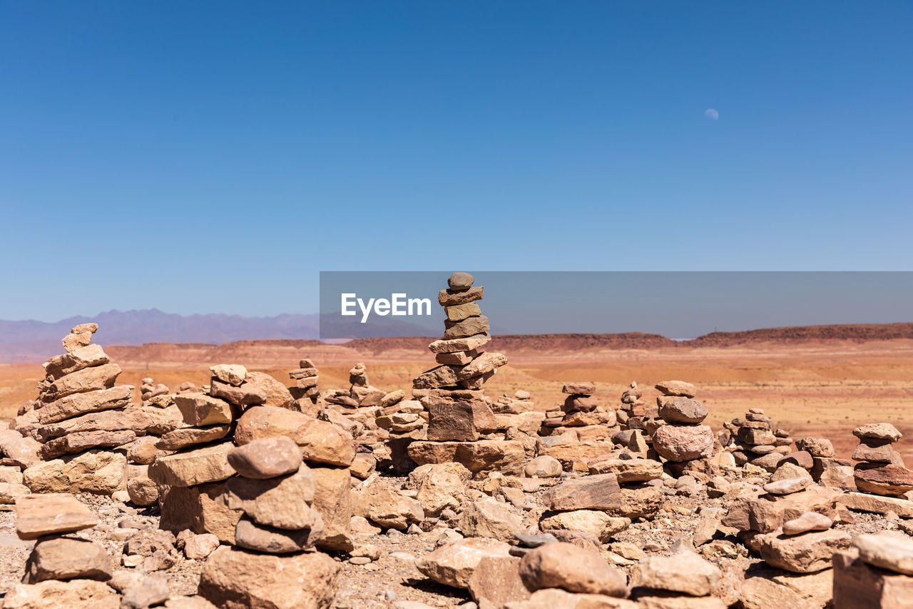 View of rock signature figurine on landscape against clear blue sky