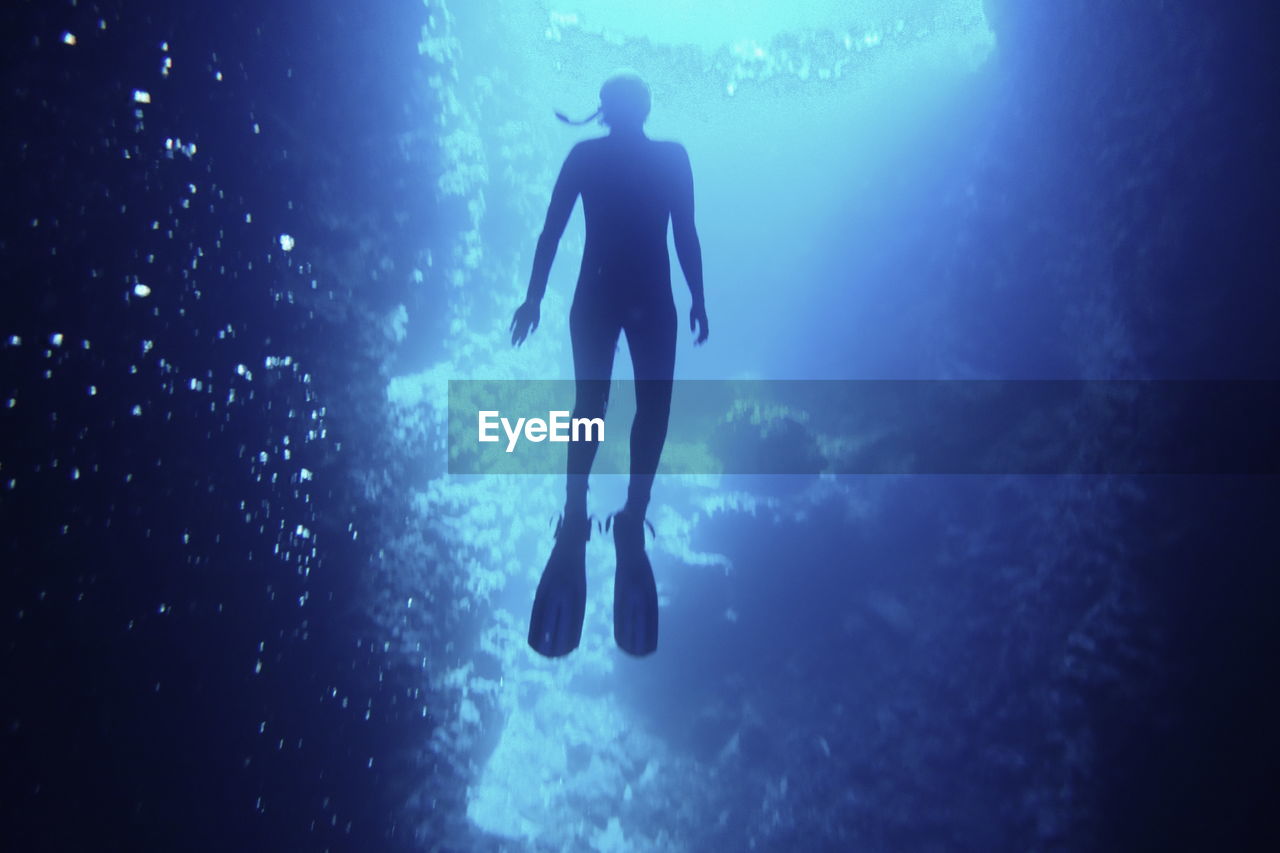 Low angle view of swimming cave diving silhouette in blue sea waters of vava'u, tonga