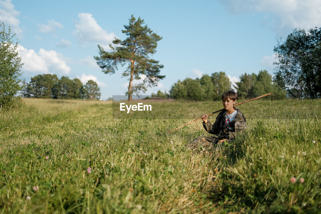 YOUNG WOMAN SITTING ON FIELD