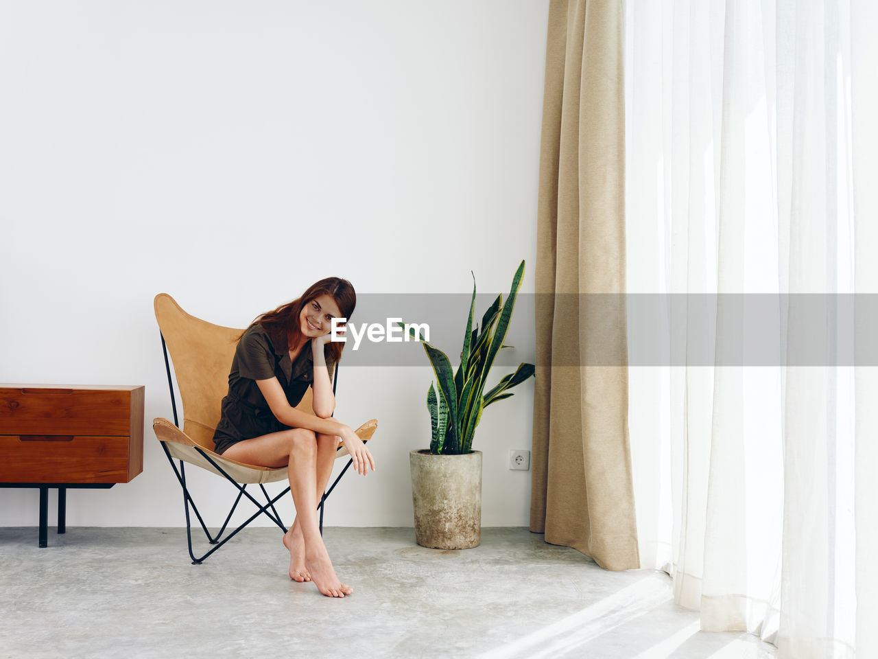 side view of woman sitting on chair at home
