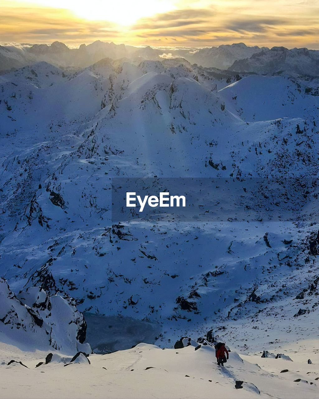 High angle view of man hiking on snowcapped mountains during sunset