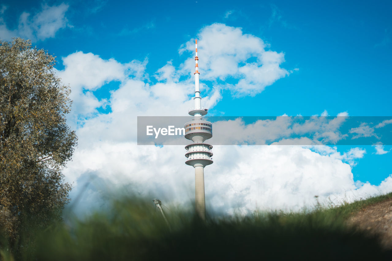 Low angle view of olympia tower against cloudy sky