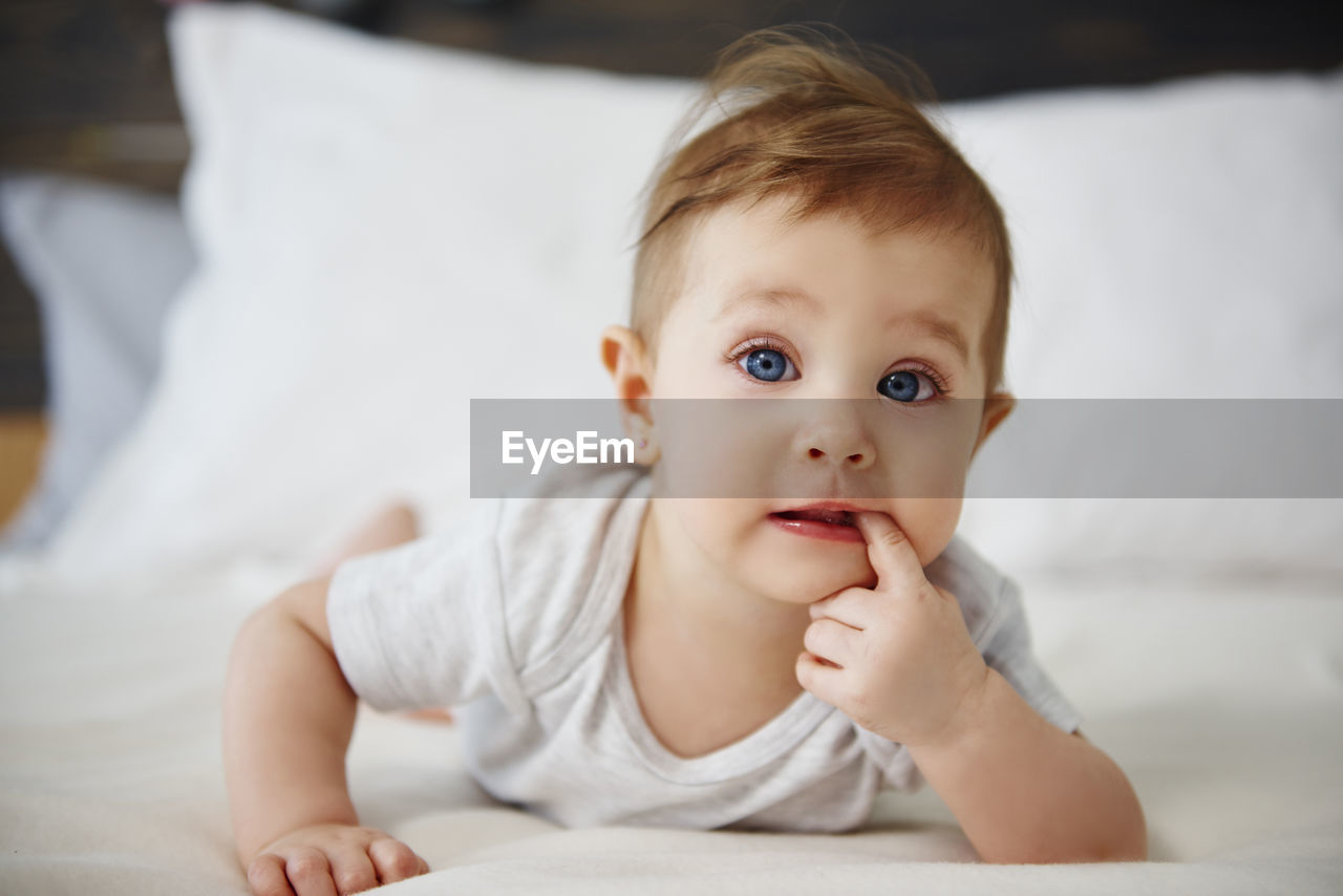 Portrait of baby girl lying on bed at home